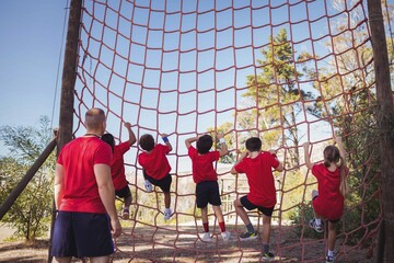 Wall Mural - trainer instructing kids in net climbing