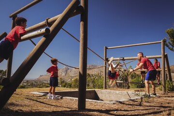 Wall Mural - trainer assisting a girl in obstacle course training