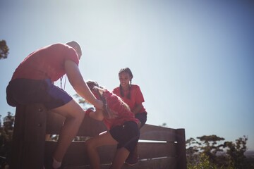 Wall Mural - trainer assisting kids to climb a wooden wall