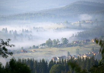  a morning light in the mountains, the village is highlighted in yellow in the fog
