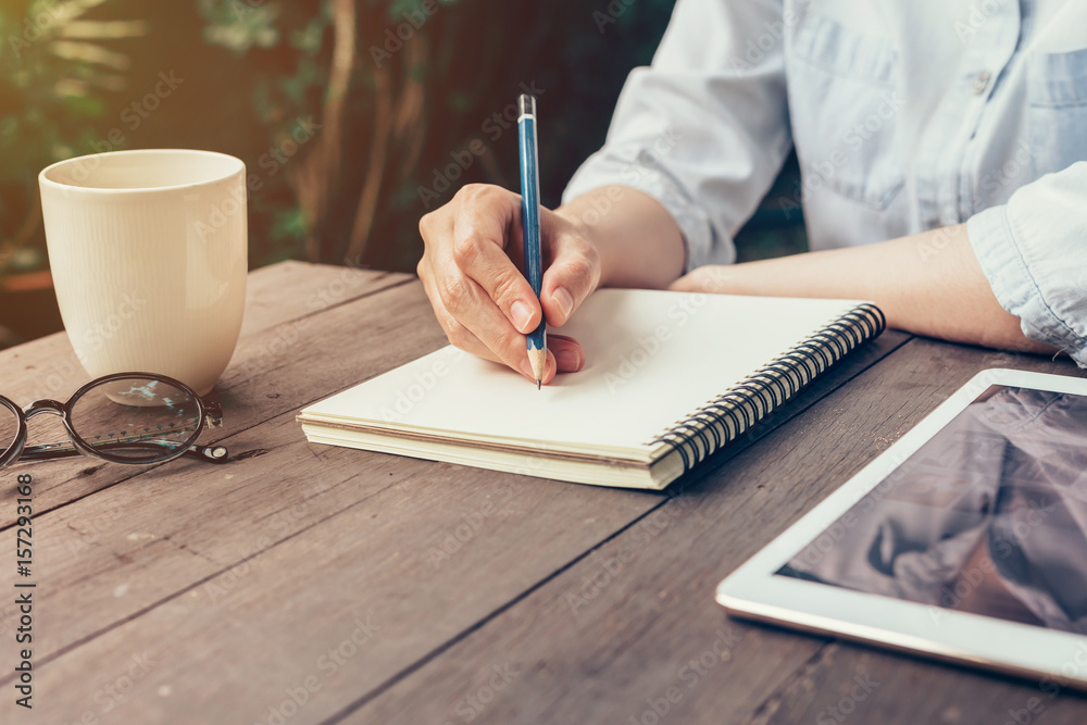 девушка пишет в блокноте ручкой за столом