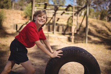 Wall Mural - portrait of smiling girl exercising with huge tyre