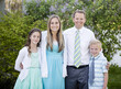 © Brocreative - Beautiful Young Family Portrait outdoors. Standing and wearing formal clothing and smiling together in a beautiful green setting