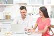 © Africa Studio - Young couple with laptop sitting at kitchen table