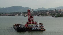 Barge And Dredger In The Bay Of Santiago De Cuba. Old City And Mountains Can Be Seen In The Background