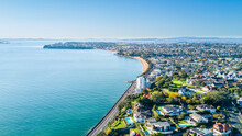 Aerial View On A Road Running Along Sea Shore With Residential Suburbs On The Background. Auckland, New Zealand.