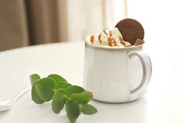 Cup with tasty cocoa drink and sweets on table