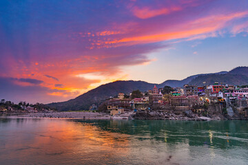 Dusk time at Rishikesh, holy town and travel destination in India. Colorful sky and clouds reflecting over the Ganges River.