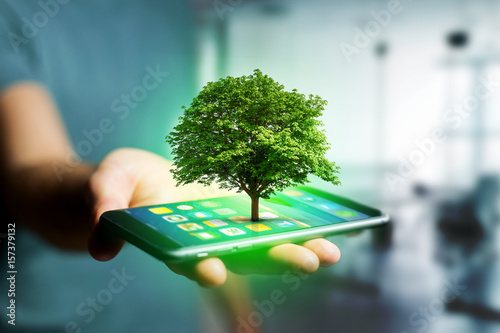 Fotografie, Obraz Green tree going out of a smartphone - Ecology concept