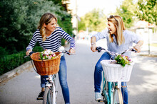 Two Young Women Exploring The City On Bicycles