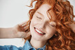 © Cookie Studio - Close up of beautiful redhead young girl smiling with closed eyes. White background.