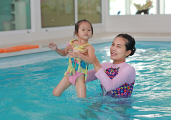 family of mother teaching kid in swimming pool.