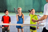 Joyful pupils learning to play tennis