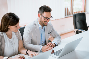 Two entrepreneurs sitting together working in an office desk with laptop