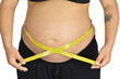 © anjokan - A pregnant woman uses a piece of measuring tape to take up the measurements of her pregnancy bump.