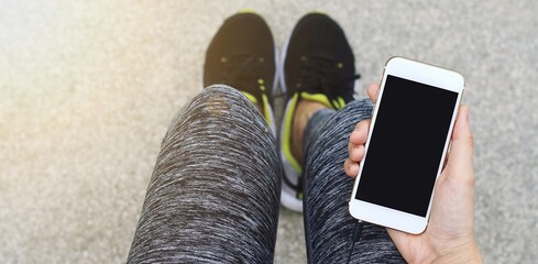 jogger using smart phone, female runner holding cell phone while taking break.