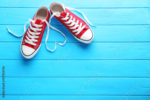Pair of red sneakers on blue wooden table Tableau sur Toile