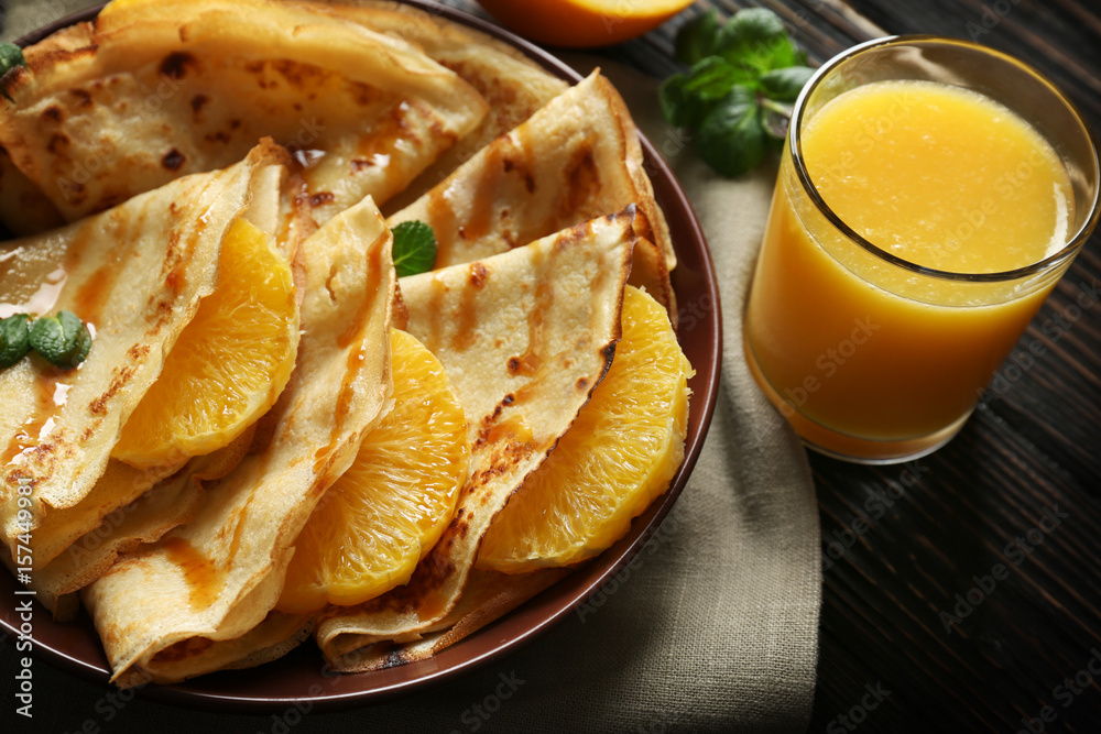 Tasty pancakes with orange slices on plate