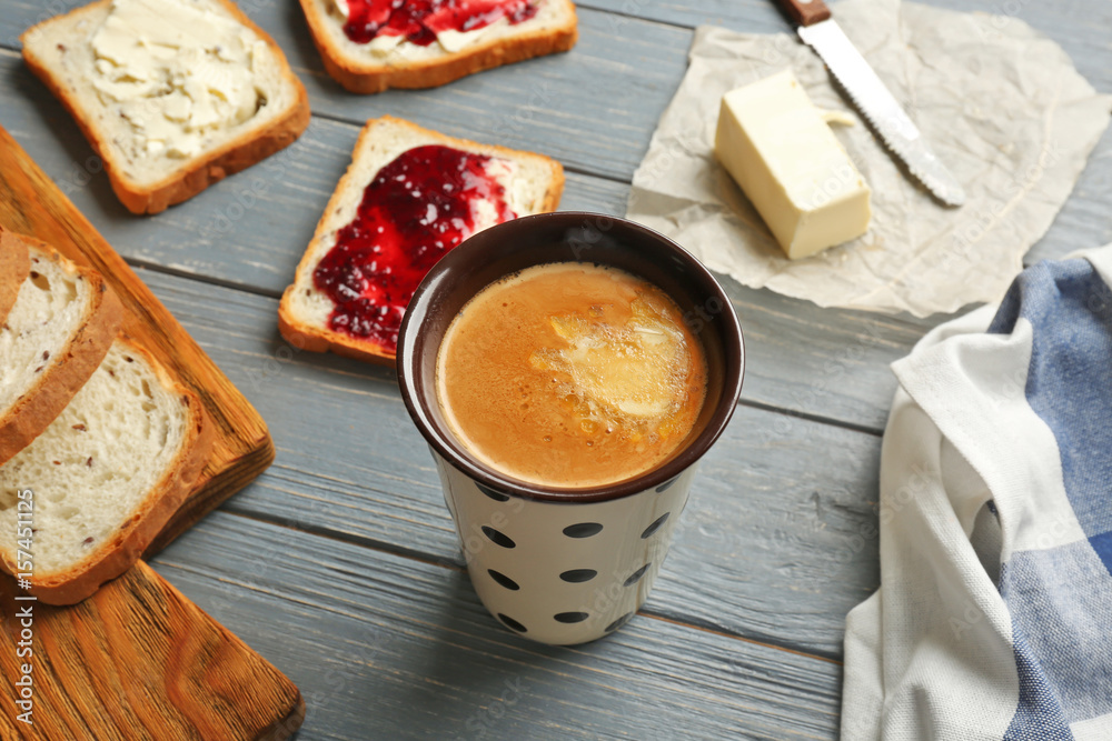 Composition with tasty butter coffee and toasts on wooden table