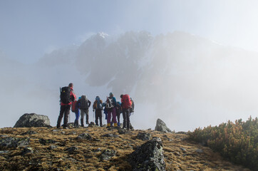 Climbers prepare themselves for the ascent of alpine peak which is partly hidden behind the fog in the background