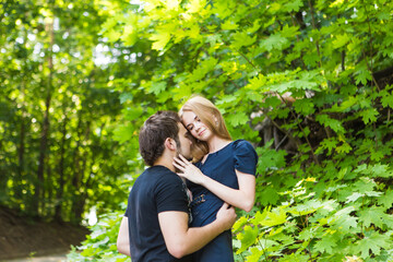 Young couple outdoor portrait. Beautiful pretty girl kissing handsome boy. Sensual photo