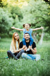 © F8  \ Suport Ukraine - Young happy family of three having fun together outdoor. Pretty little daughter on her father back with happy raised hands. Parents and girl look happy and smile.
