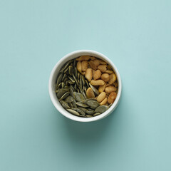 Wall Mural - Healthy eating, snack. Nuts and seeds in white bowl, closeup, flat position