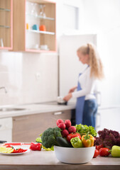 Fresh vegetables on table with woman in background