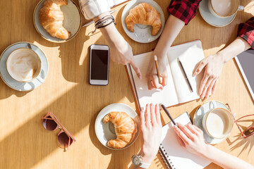 overhead view of young women sitting at coffee break with digital devices, business lunch