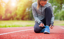Athletic Woman On Running Track Tying Shoe Laces Before Start Workout