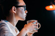 © LIGHTFIELD STUDIOS - Side view of young businesswoman in eyeglasses holding cup while working late in office