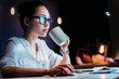 © LIGHTFIELD STUDIOS - Young businesswoman in eyeglasses holding cup while working late in office