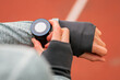 Athletic woman on running track setting up her smart watch fitness accessories