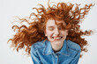 © Cookie Studio - Attractive cheerful redhead girl with flying curly hair smiling laughing with closed eyes over white background.