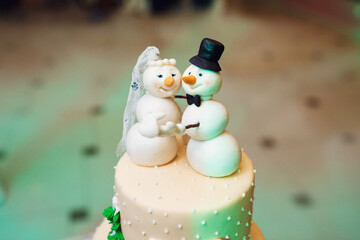 Wall Mural - White wedding cake with snowmen dressed like newlyweds on the top