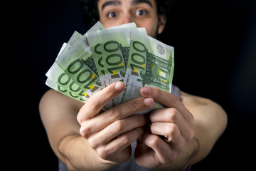 isolated 100 euro cash holding on a black background.