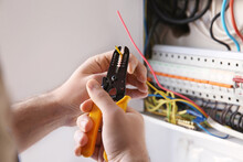 Young Electrician Skinning A Wire In Light Room