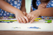 © pingpao - Two children hands helping and trying to connect jigsaw puzzle piece to learn to find solution