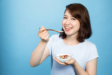 young woman eating yogurt on blue background. Intestinal flora.