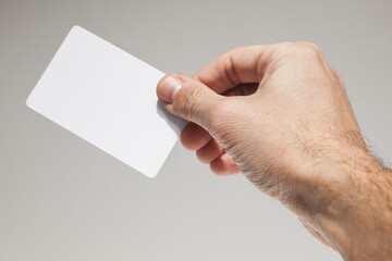 Male hand with white empty card over gray wall