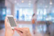 © littlestocker - Hands holding mobile phone with blurred image of shopping mall