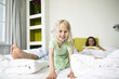 © Westend61 - Portrait of smiling little girl on hotel bed with her parents