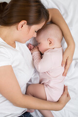 Fototapete - Mother and baby sleep in bed. Mom embraces her little daughter.