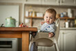 © poplasen - Portrait of blonde baby boy sitting at the dinner table eating pomegranate