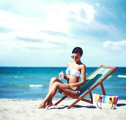 Wall Mural - Attractive young girl in bikini sunbathing on beach. Traveling, holiday, vacation concept.