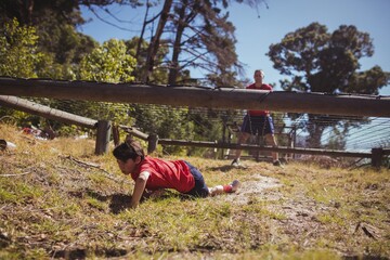 Wall Mural - boy crawling under the net during obstacle course training