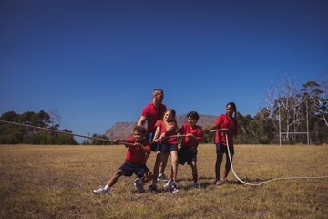 Wall Mural - trainer assisting kids in tug of war during obstacle