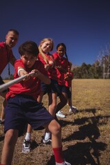 Wall Mural - trainer assisting kids in tug of war during obstacle
