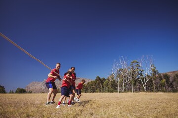 Wall Mural - trainer assisting kids in tug of war during obstacle