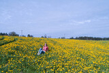 Fototapeta Kuchnia - Flight over a girl lying on a green grass in yellow field flowers